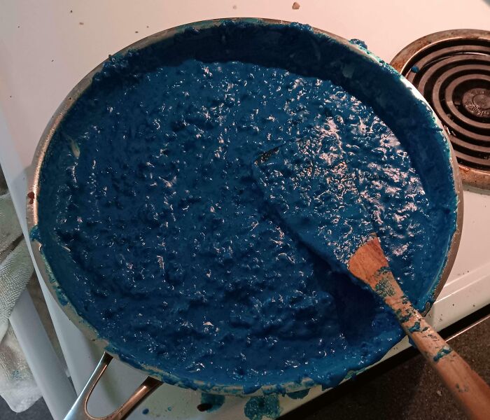 Blue, lumpy Bananasausage mixture in a pan with a wooden spoon, creating a Food Crime that needs a priest.