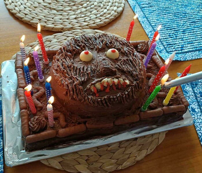 A monstrous chocolate cake with glowing eyes, bloody teeth, and candles being lit, fitting the "Bananasausage" theme.