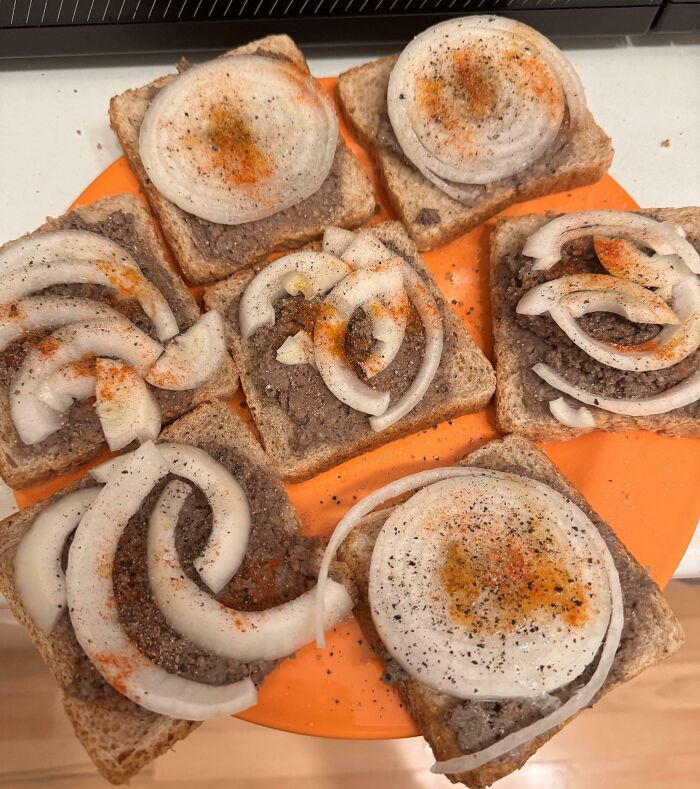 An orange plate with slices of bananasausage toast topped with raw onions, black pepper, and paprika. Food crimes.