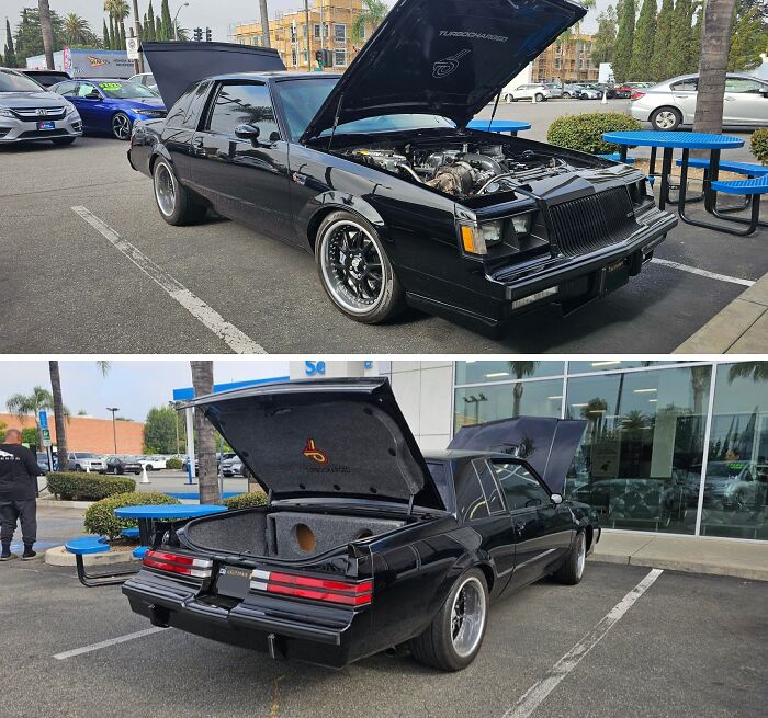 Black classic car with hood and trunk open in parking lot, showing engine and custom interior by car mechanics.