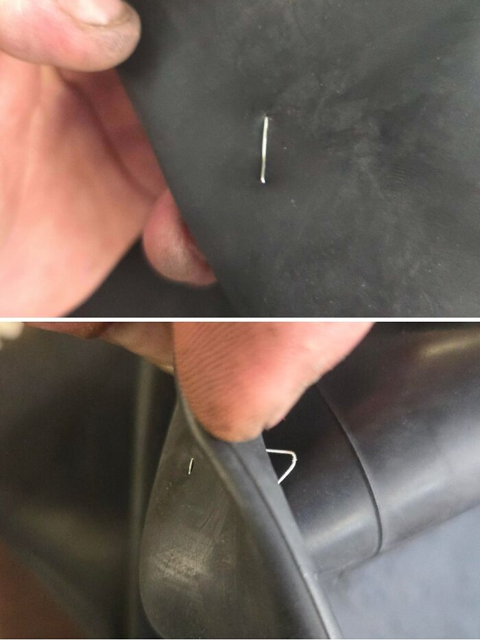 Close-up of a car mechanic showing a sharp metal staple embedded in a tire inner tube for repair evidence.