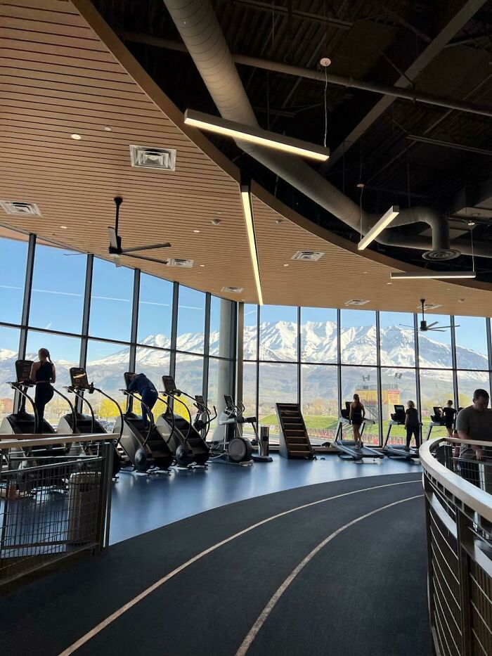 People exercising in a modern gym with large windows overlooking snow-capped mountains. A gentle reset button for your day.