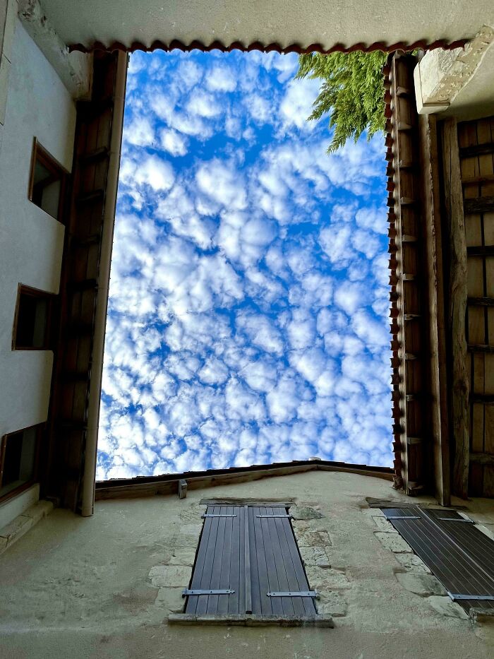 A beautiful sky full of white, fluffy clouds seen from between old buildings provides a satisfying picture and gentle reset.