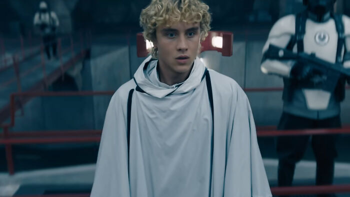 Young actor in a white cloak from the new Hunger Games trailer recreating an iconic moment amid a futuristic setting.