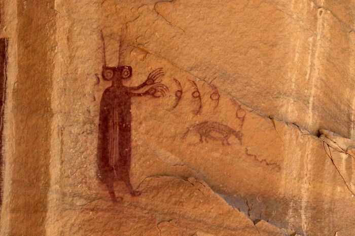 Ancient rock art depicting a mysterious figure and symbols, representing unexplained events and urban myths.