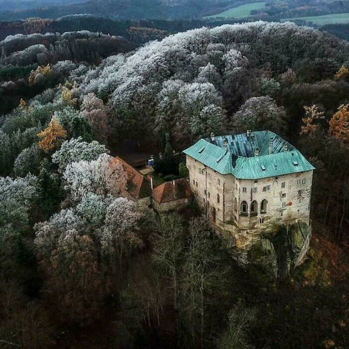 Ancient castle perched on a rocky cliff surrounded by misty forest, evoking mysterious events and urban myths atmosphere.