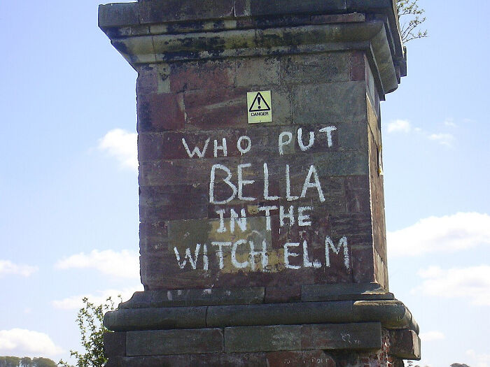 Graffiti on old brick pillar reading who put Bella in the witch elm relating to mysterious events and urban myths.