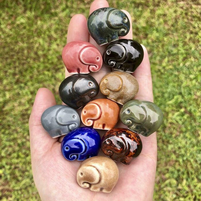 A hand holding heartwarming colorful elephant figurines symbolizing positivity and joy in a natural outdoor setting.