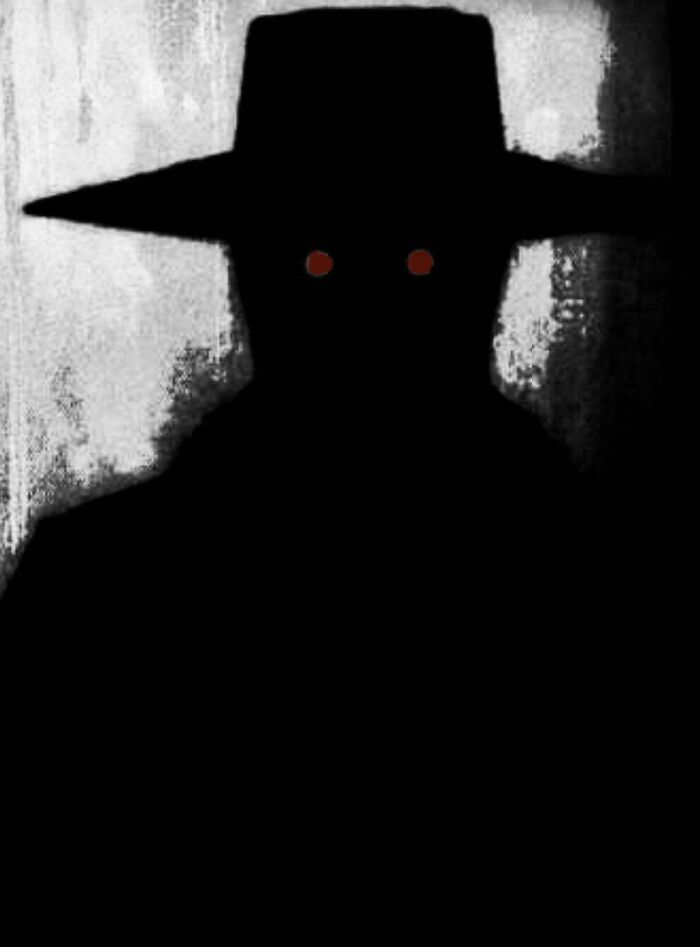 Silhouette of a mysterious figure wearing a wide-brimmed hat with glowing red eyes, evoking urban myths and mysterious events.