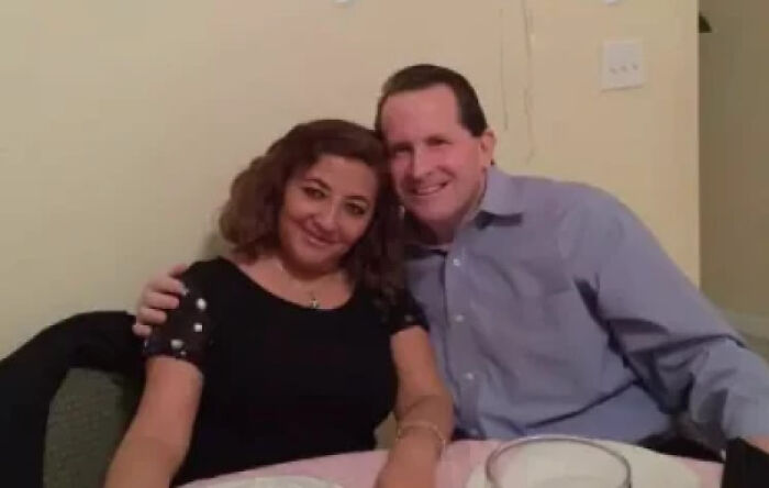 Couple smiling warmly and embracing each other at a table, radiating heartwarming positivity and connection.