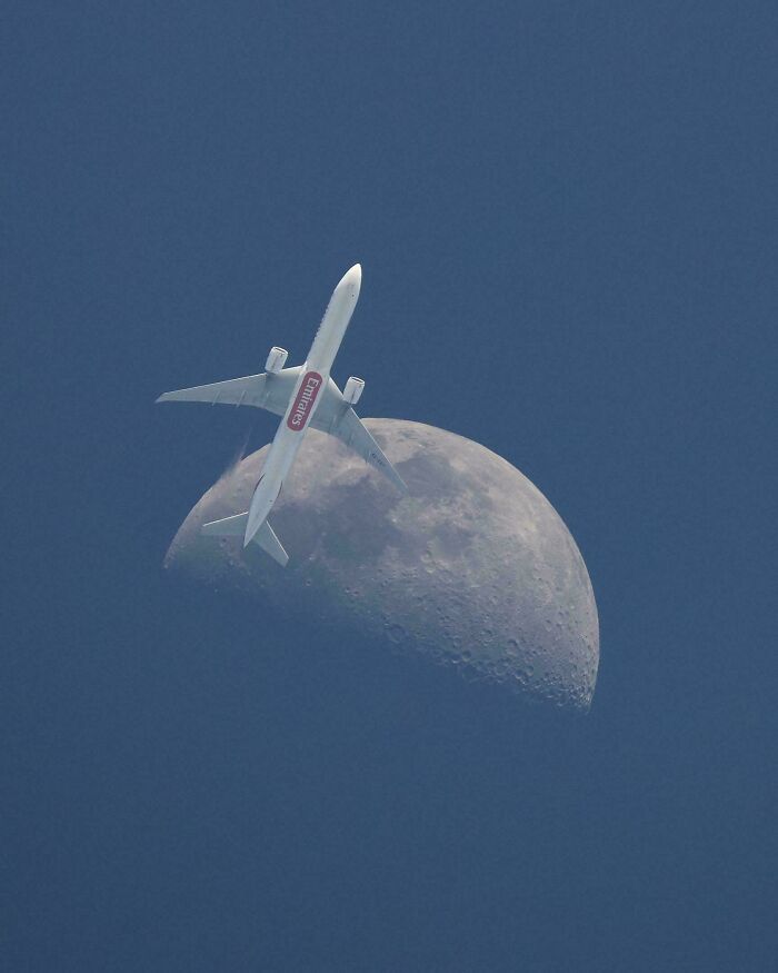 An Emirates plane appears to fly past a half-moon against a deep blue sky, a satisfying picture for a gentle reset.