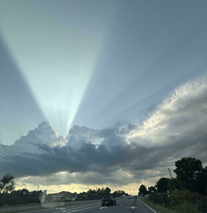 Sunbeams pierce through dramatic clouds over a highway, offering a satisfying picture for a gentle reset.