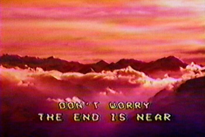Glitchy vaporwave style image with red mountains and clouds and text saying the end is near, confusing and unhinged.