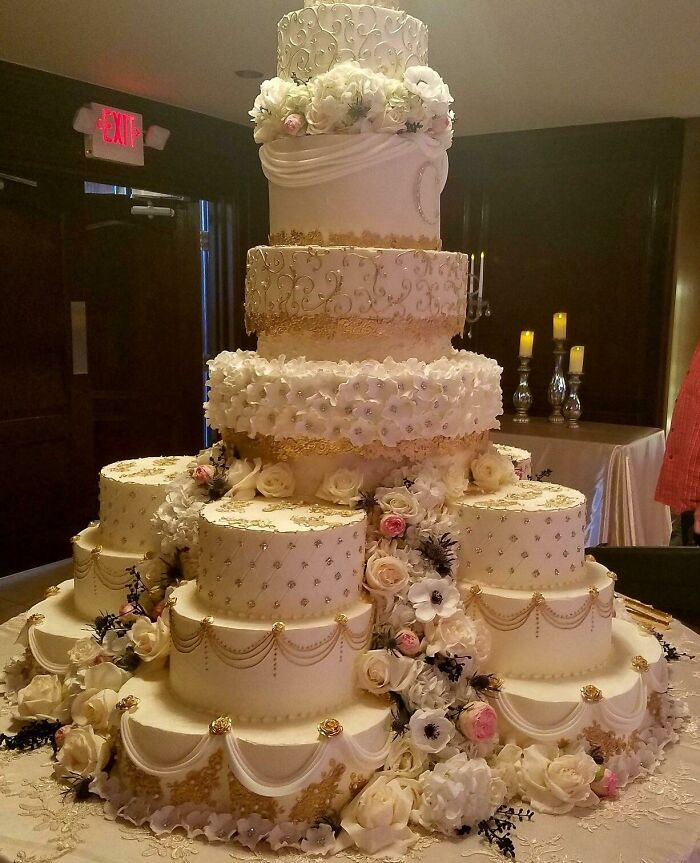 Extravagant multi-tiered wedding cake adorned with intricate floral decorations and gold detailing for trashy wedding stories.