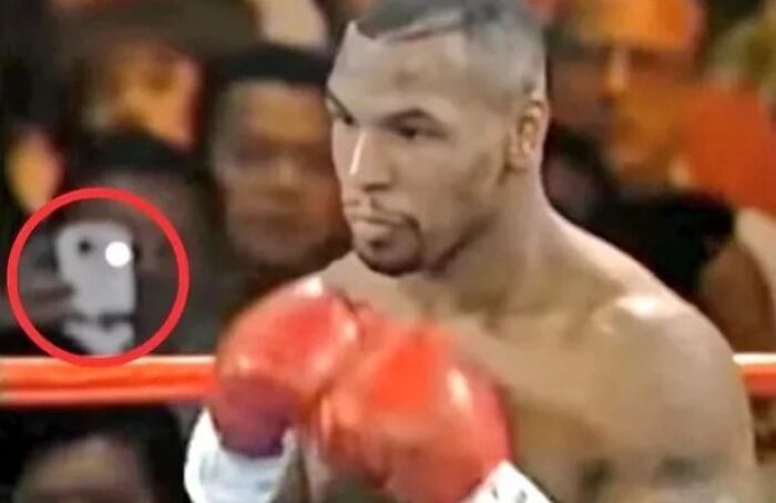 Boxer in red gloves inside ring with a mysterious figure captured in the background, highlighting unexplained urban myths and events.