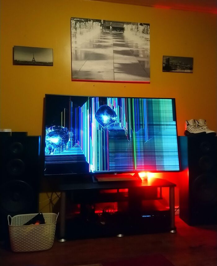 A severely cracked TV screen displaying colorful lines, reflecting a red light. This image shows red flags in a relationship.