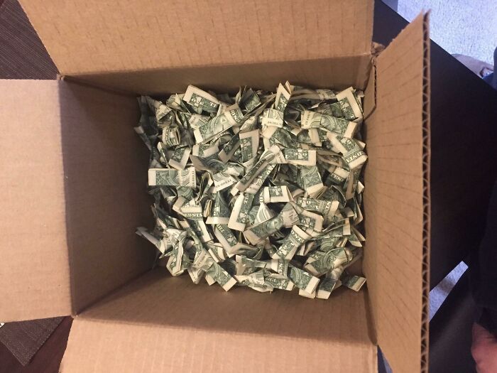 Open cardboard box filled with crumpled one dollar bills representing trashy and tacky wedding stories.