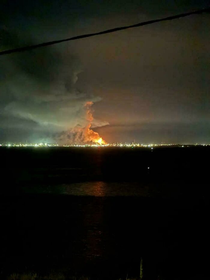 A large fire illuminates the night sky over a distant city or industrial area, creating an interesting Aussie post.
