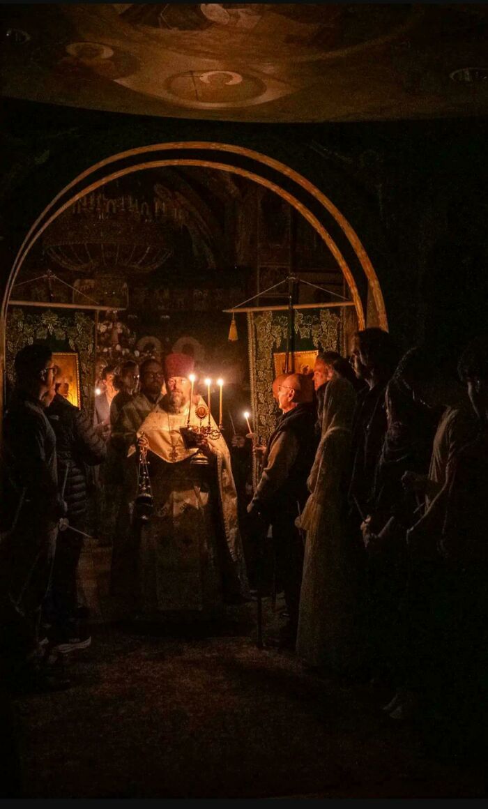 An Accidental Renaissance moment featuring an Orthodox priest holding candles in a dimly lit church.