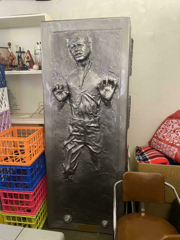 A life-sized Han Solo in carbonite replica, standing upright in a cluttered room. An unusual possession with true value.