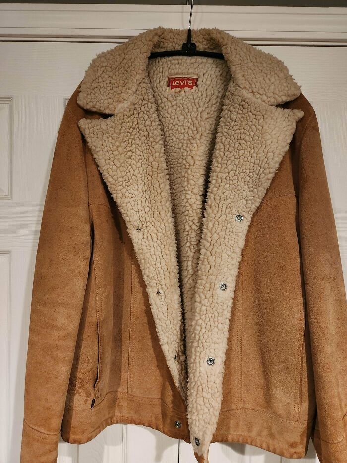 A brown Levi's sherpa jacket hanging on a white door. Its soft, unusual possession may have a surprising true value.