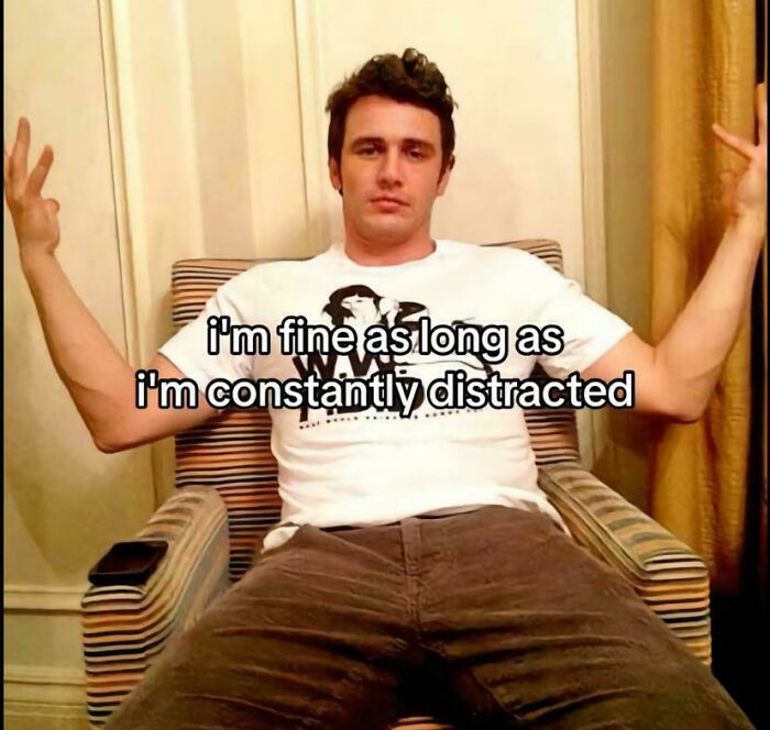 A relatable meme featuring James Franco seated, arms raised, with text: "I'm fine as long as I'm constantly distracted."