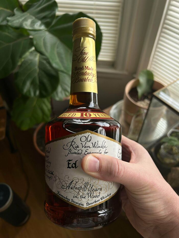 A hand holds a rare bottle of Old Rip Van Winkle bourbon. People understand the true value of their unusual possessions.
