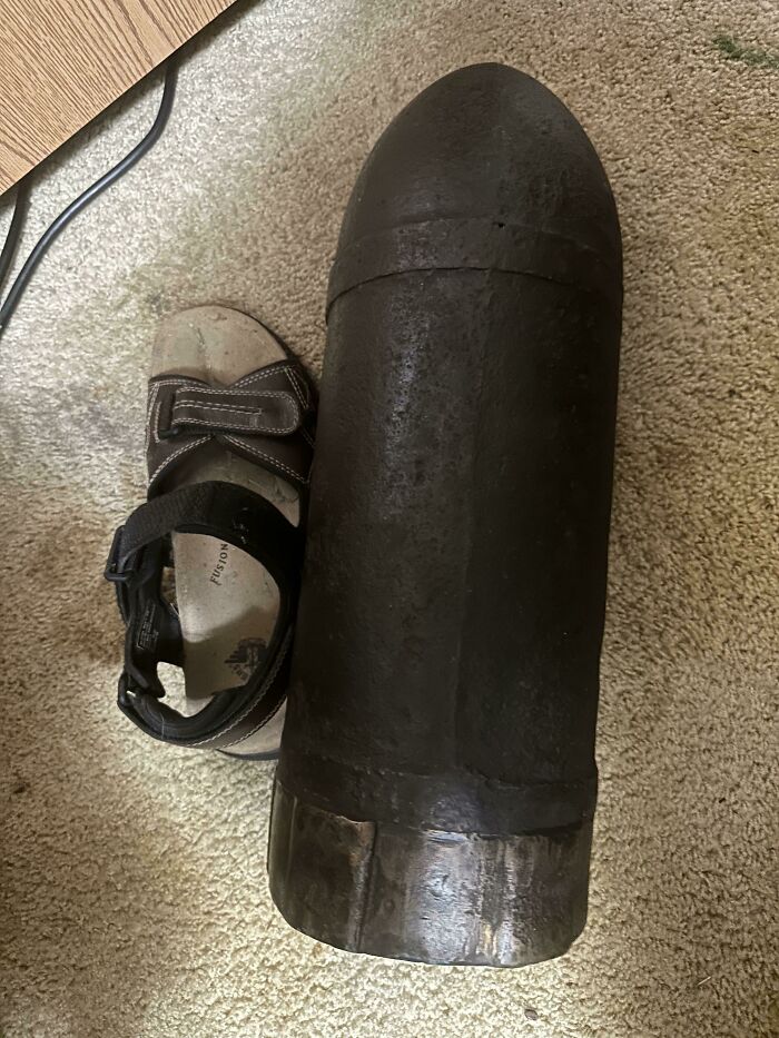 A large, dark, unusual possession resembling a shell next to a sandal for scale on a carpet, highlighting its true value.