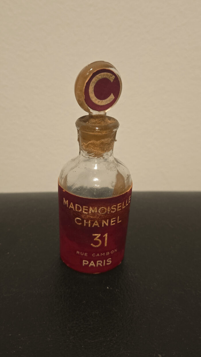 A small vintage Chanel Mademoiselle perfume bottle with a unique stopper featuring a gold 'C' logo. An unusual possession.