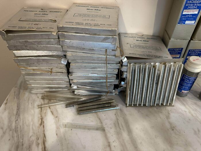 Dental Silver Alloy packs and vials, some opened, showcasing the unusual possessions' true value on a marble surface.