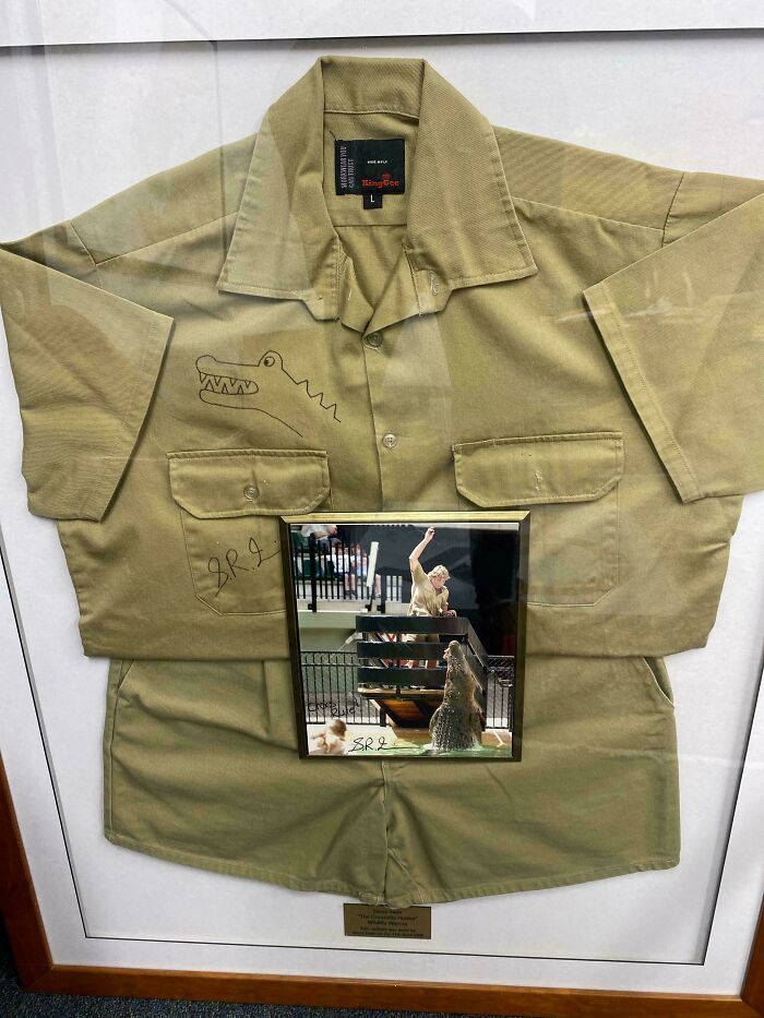 Unusual possession: framed Steve Irwin uniform with crocodile drawing and a photo of him feeding a crocodile, revealing its true value.