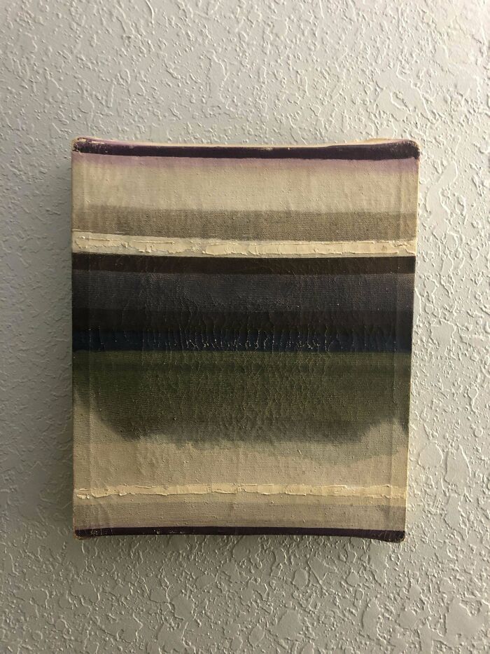 An abstract painting with horizontal stripes of muted purple, cream, dark grey, and green. A unique possession on a textured wall.