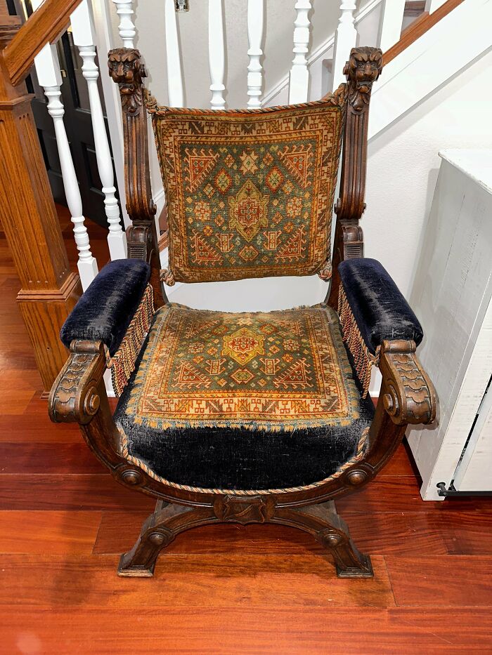 A unique ornate wooden chair with blue velvet armrests and patterned tapestry cushions, showcasing an unusual possession.