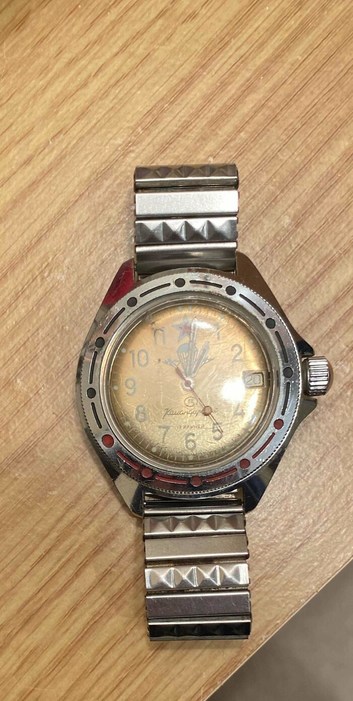 A worn silver watch with a gold-colored face and metal band. This unusual possession could have true value.
