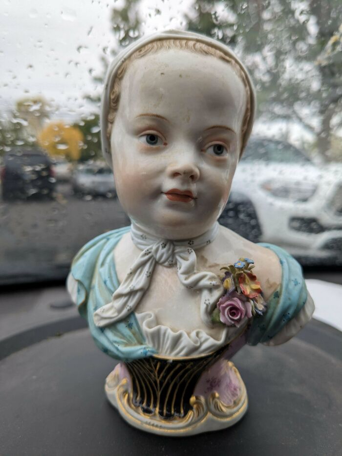 Porcelain bust of a young girl with flowers, showcasing the true value of unusual possessions, on a rainy day.