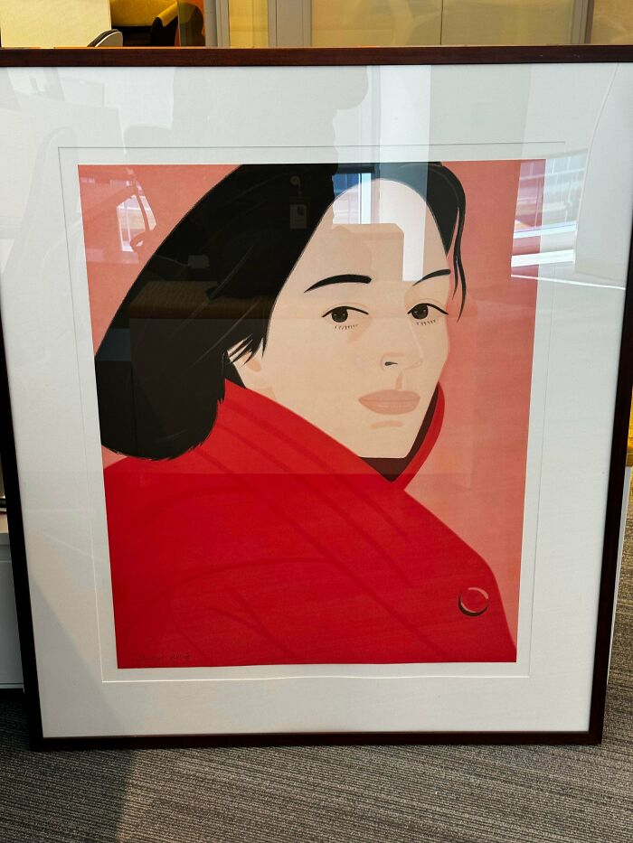 A framed graphic print of a woman in a red coat looking over her shoulder. Might be an unusual possession!