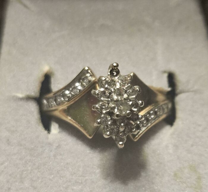 A gold ring with a diamond cluster in the center and more diamonds along the band, showcasing unusual possessions.
