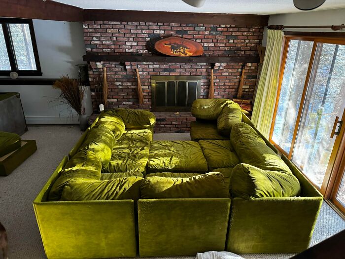 A vintage chartreuse modular sofa filling a living room with a brick fireplace, highlighting unusual possessions.