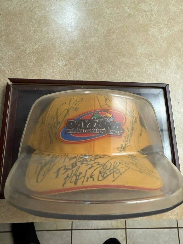 A Daytona International Speedway hat, signed by multiple people, displayed in a clear case. Unusual possession with true value.