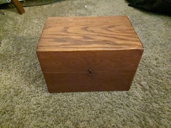 A wooden box with a metal clasp on a textured carpet. Discover the true value of unusual possessions.