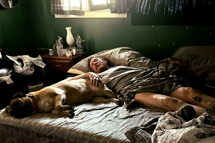 An Accidental Renaissance scene of a man and his dog sleeping peacefully in bed bathed in dramatic light.