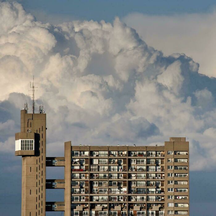 Brutalist apartment building under dramatic cloudy sky in urban hell