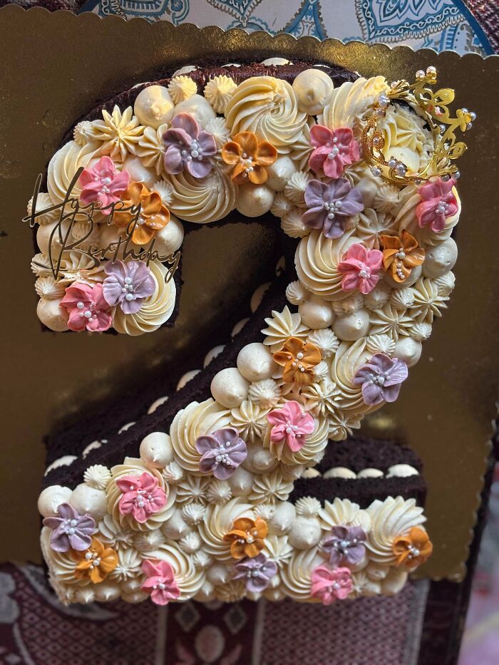 Number two birthday cake decorated with colorful flowers and cream frosting