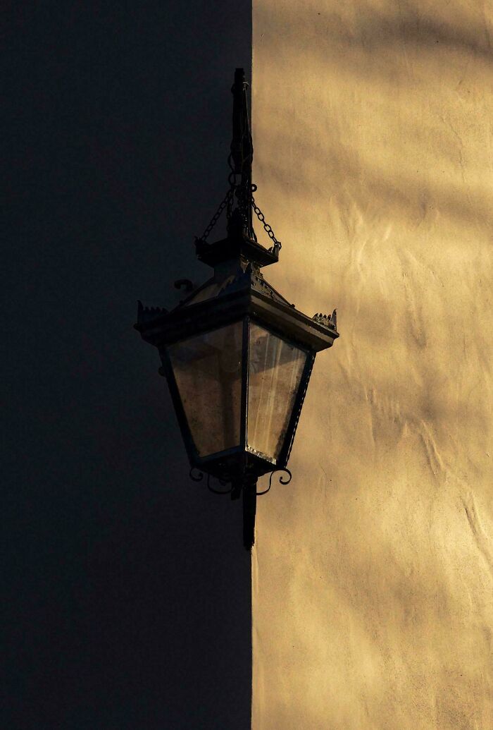 An antique lantern partially lit by sunlight on a building corner, offering a gentle reset feel.