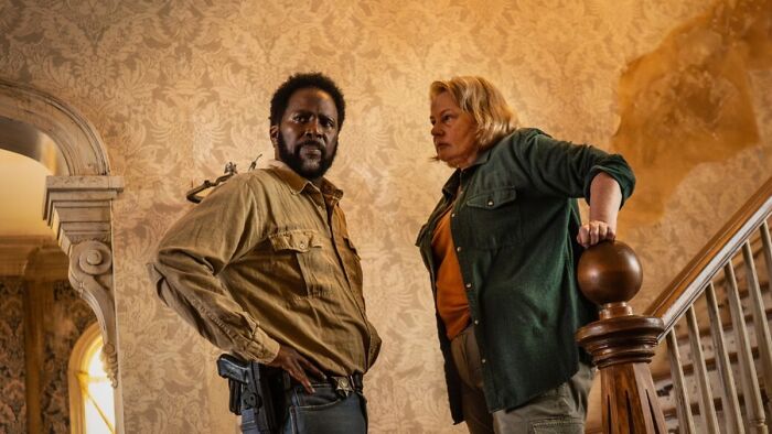 Dois personagens da estreia da 4ª temporada parados dentro de uma casa, destacando uma reviravolta aterrorizante na série.