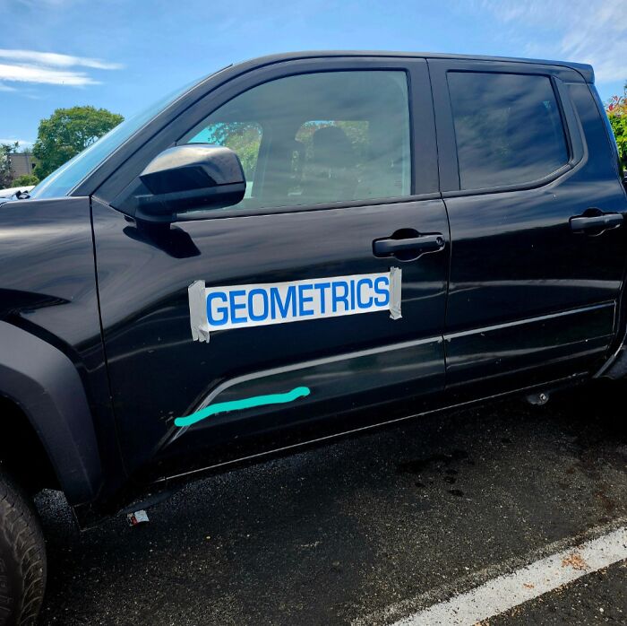 Black car with a dent and a taped sign reading geometrics illustrating designers working without common sense humorously.