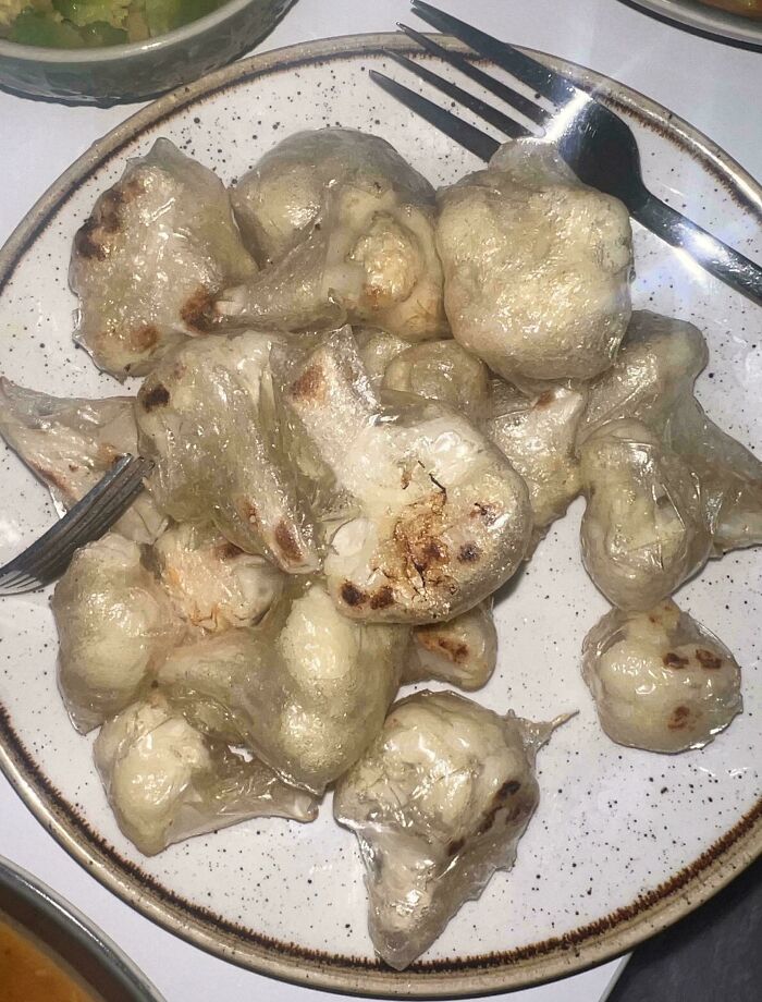 A plate of oddly shaped, translucent, pale food items, some with browned spots. A real bananasausage food crime.