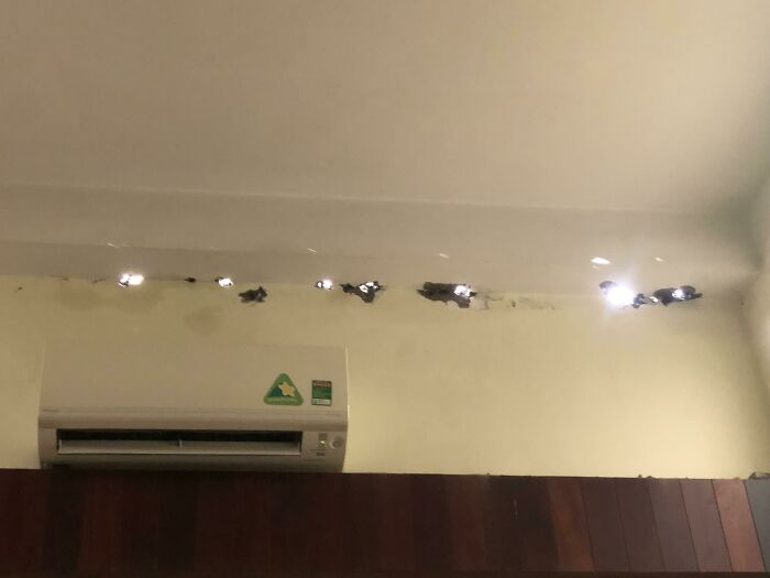 A damaged ceiling with holes and water stains above an air conditioner, showing home improvement fails.