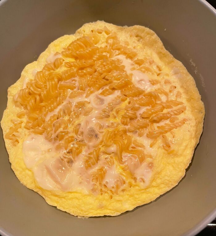 An omelet with uncooked ramen noodles and white sauce, an example of a Bananasausage food crime.