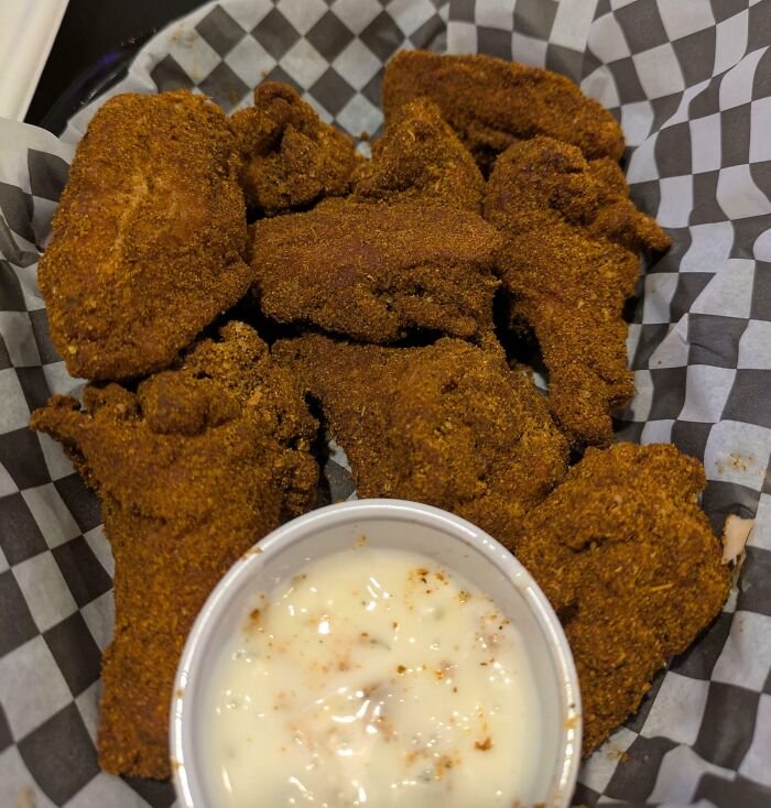 Crispy bananasausage bites with a creamy dipping sauce, served in a checkered basket. A true food crime.